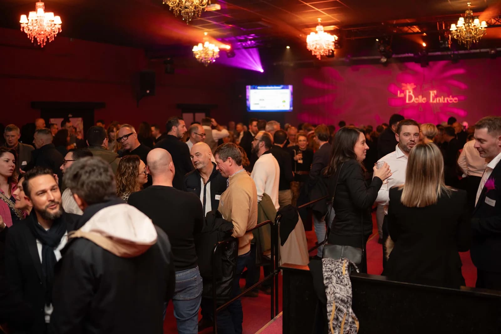 Les invités échangent dans la salle du cabaret, sous les lustres